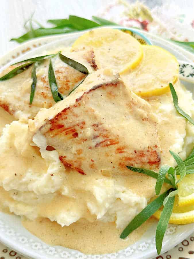 chicken tarragon plated on top of mashed potatoes and topped with creamy sauce