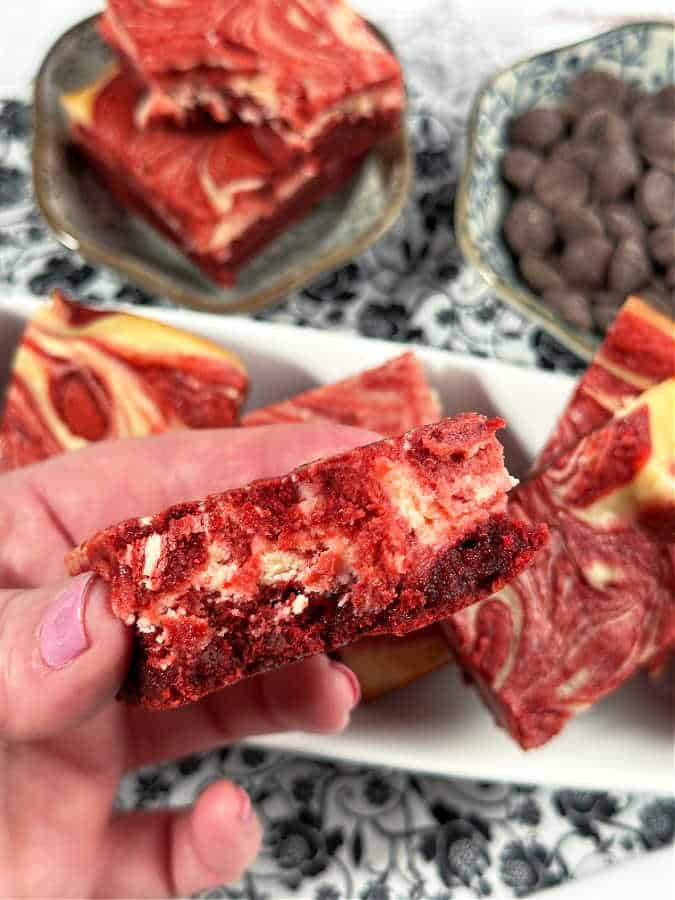 taking a bite of a red velvet cheesecake brownie