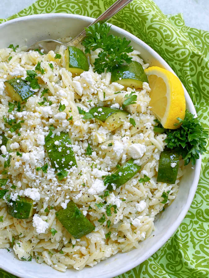 orzo pasta salad in a big serving bowl garnished with lemon slices