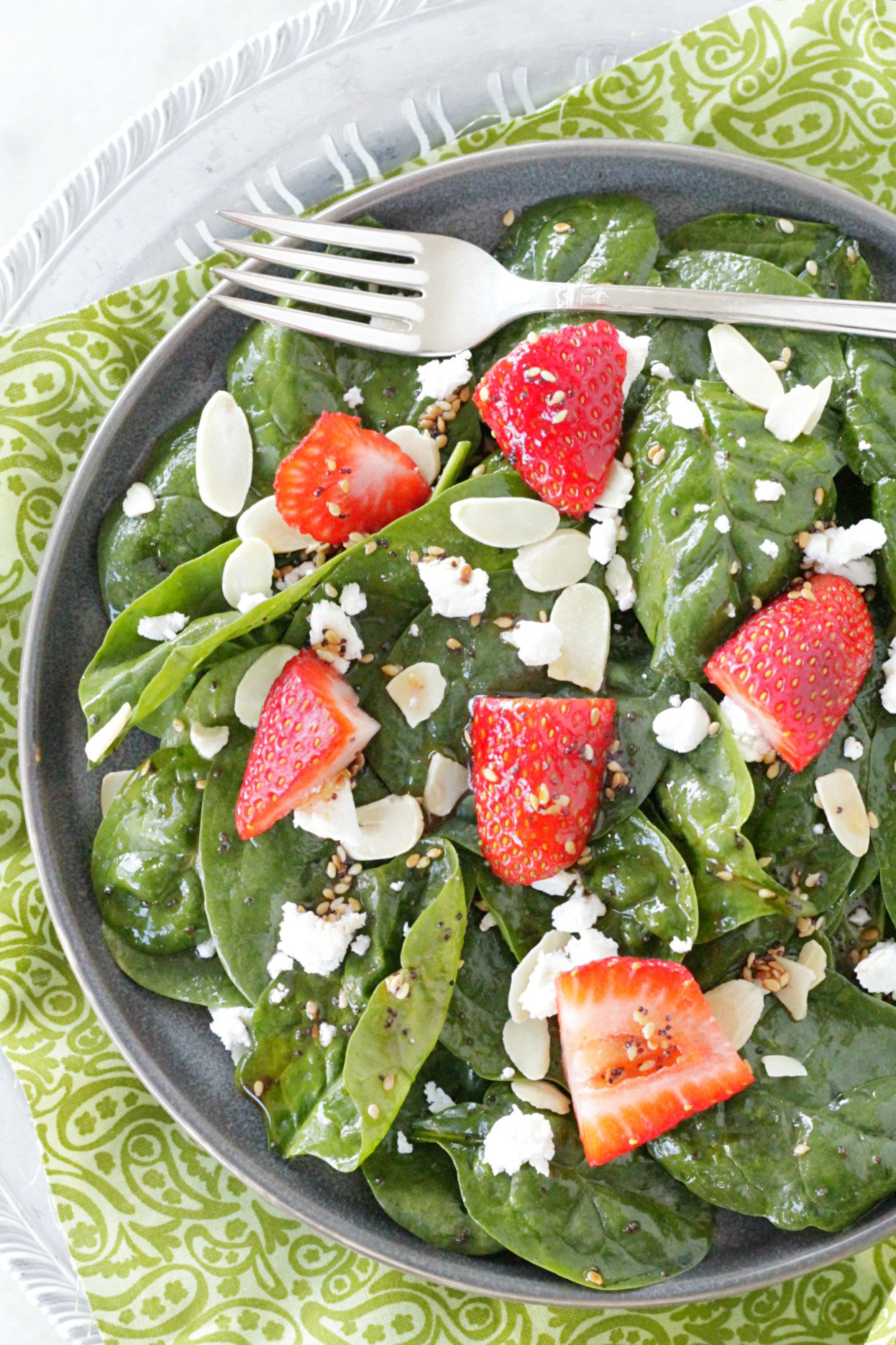 top view of spinach strawberry salad on gray plate with fork on top