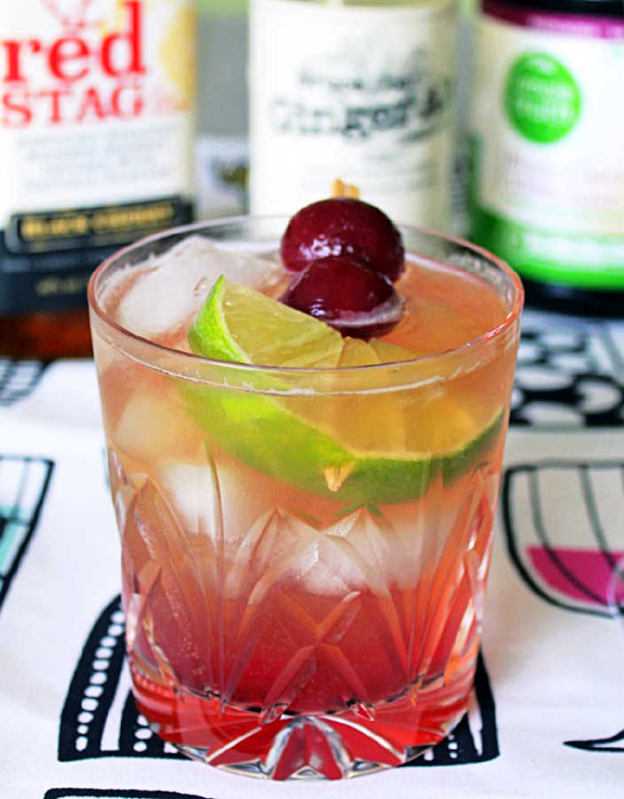 a cherry bourbon cocktail garnished with homemade maraschino cherries