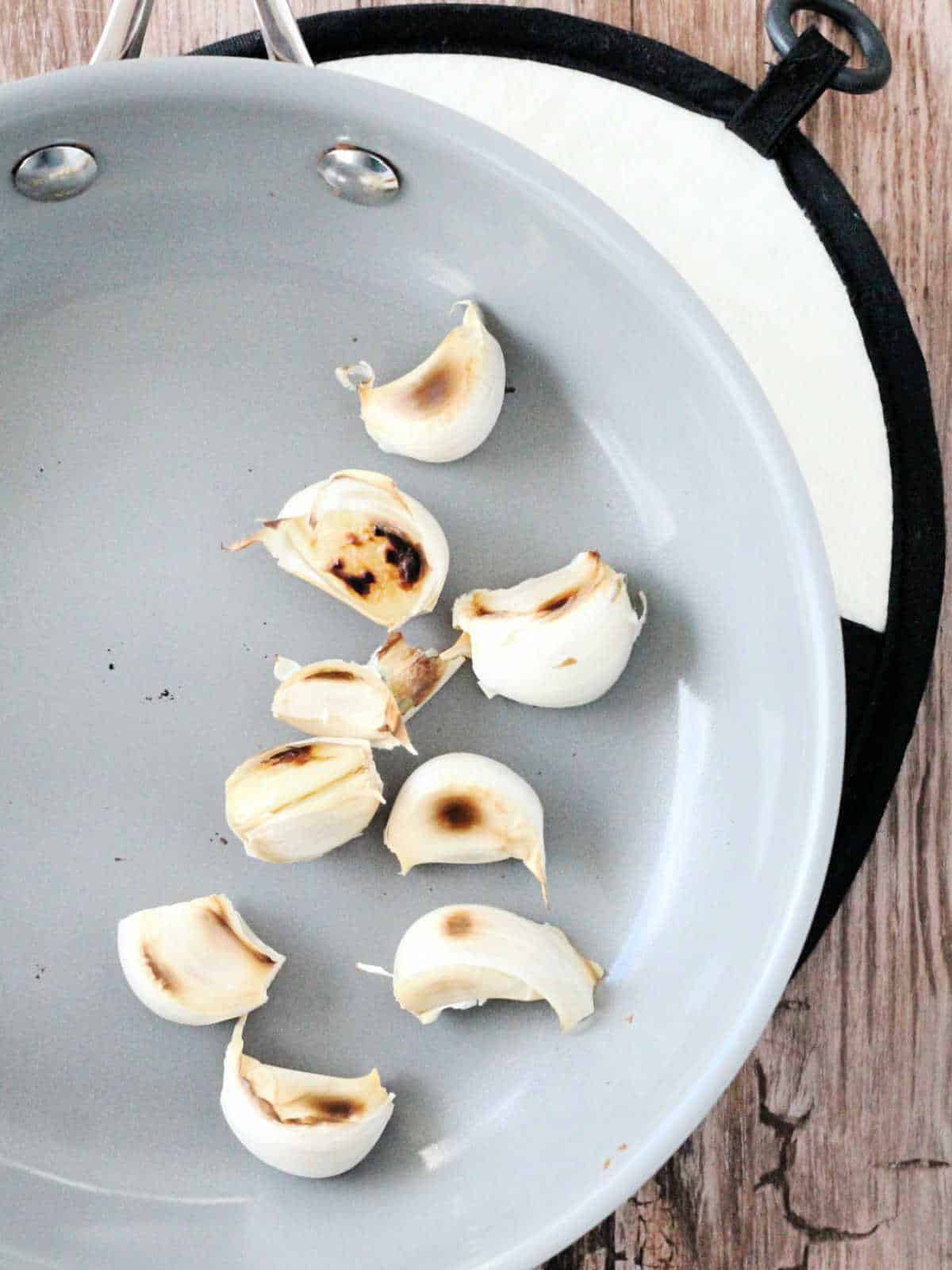 showing non-stick skillet with toasted garlic cloves