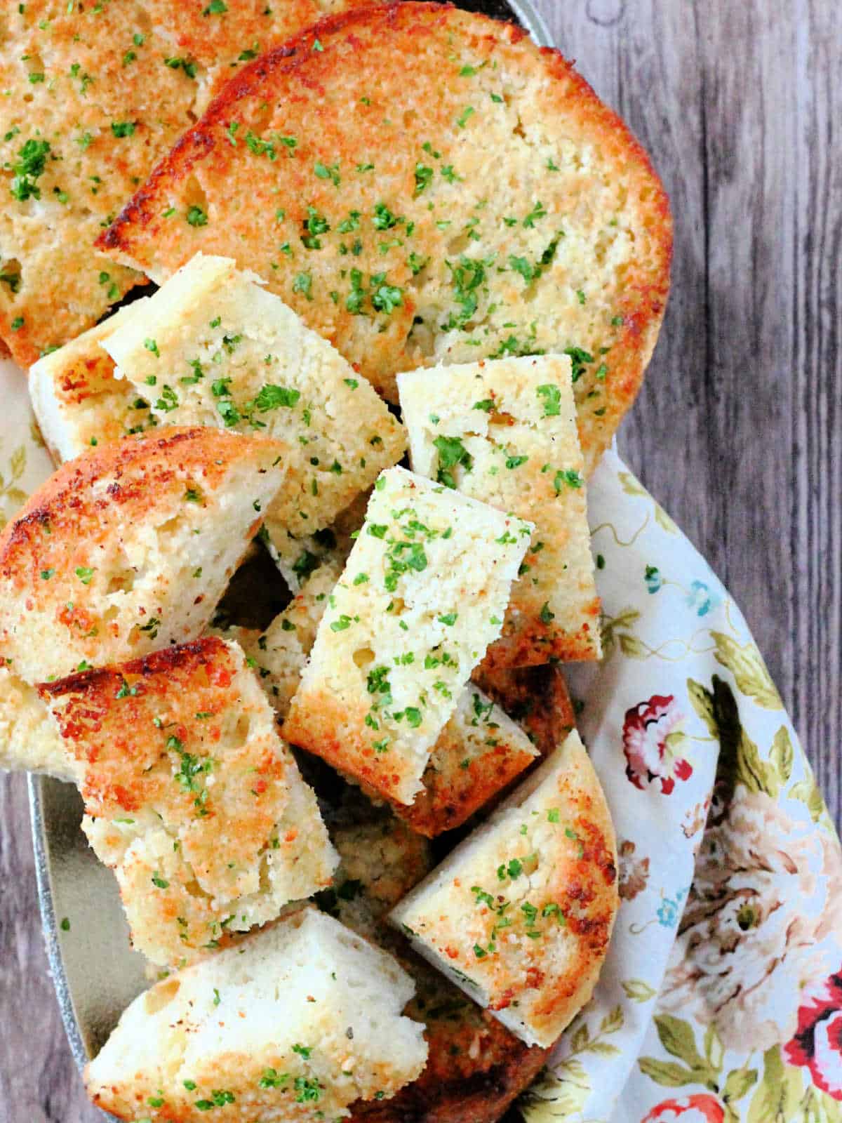 a platter of garlic bread garnished with fresh chopped parsley