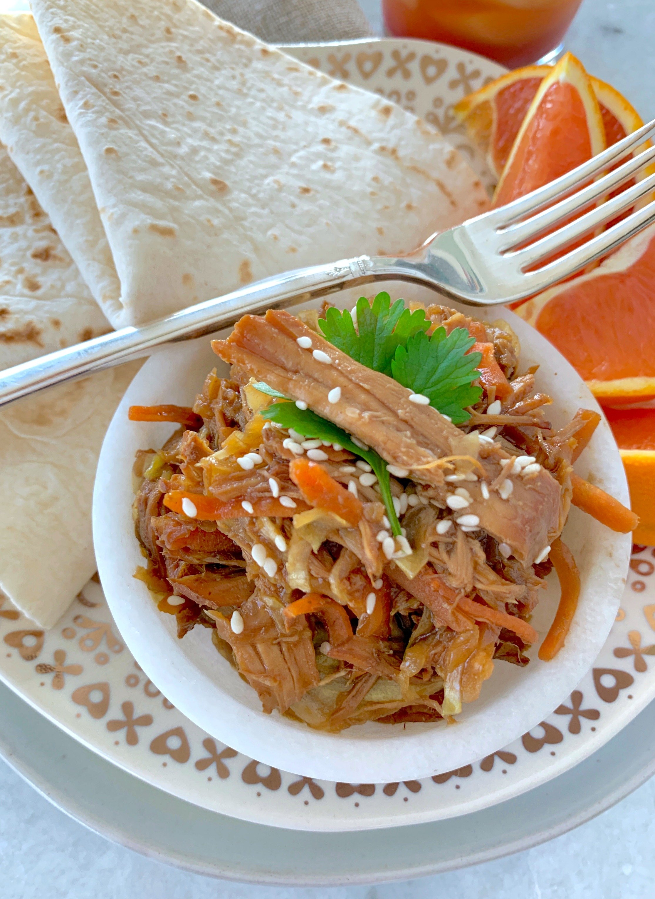 slow cooker moo shu pork on plate with tortillas and orange slices