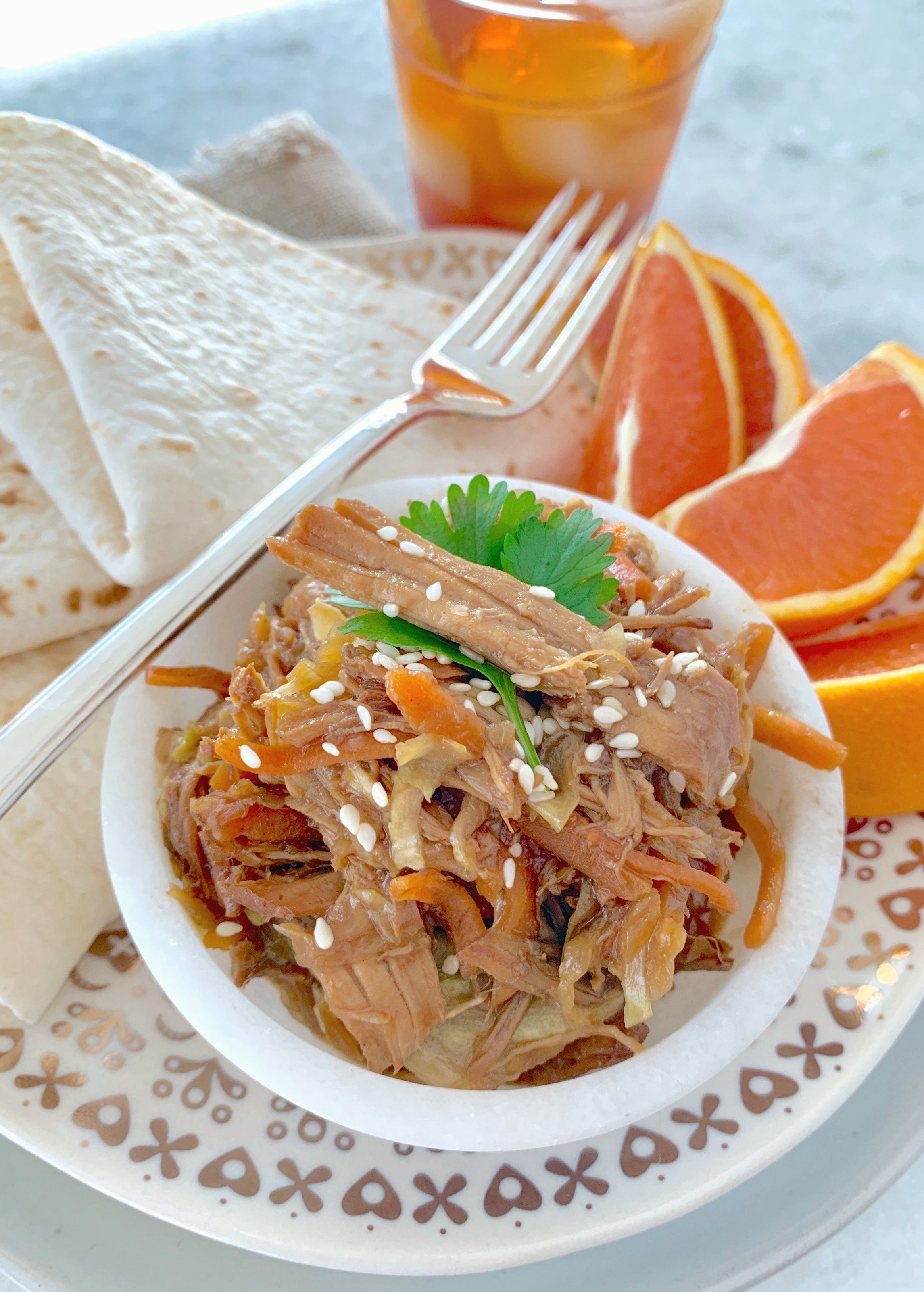 slow cooker moo shu pork on a plate with tortillas and orange slices