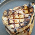 perfectly grilled pork chops stacked on a plate