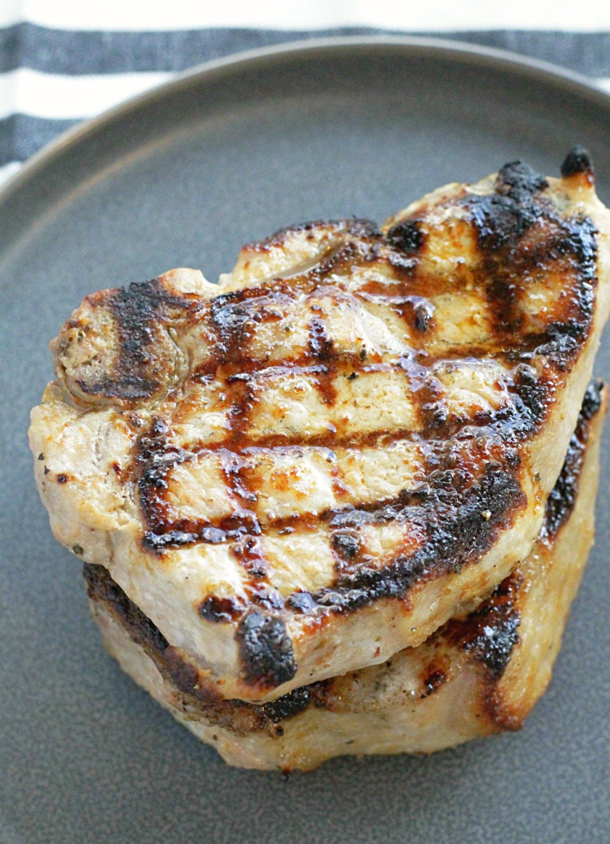 perfectly grilled pork chops stacked on a plate