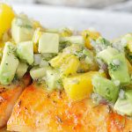 close up view of citrus salmon with avocado and orange salsa on top