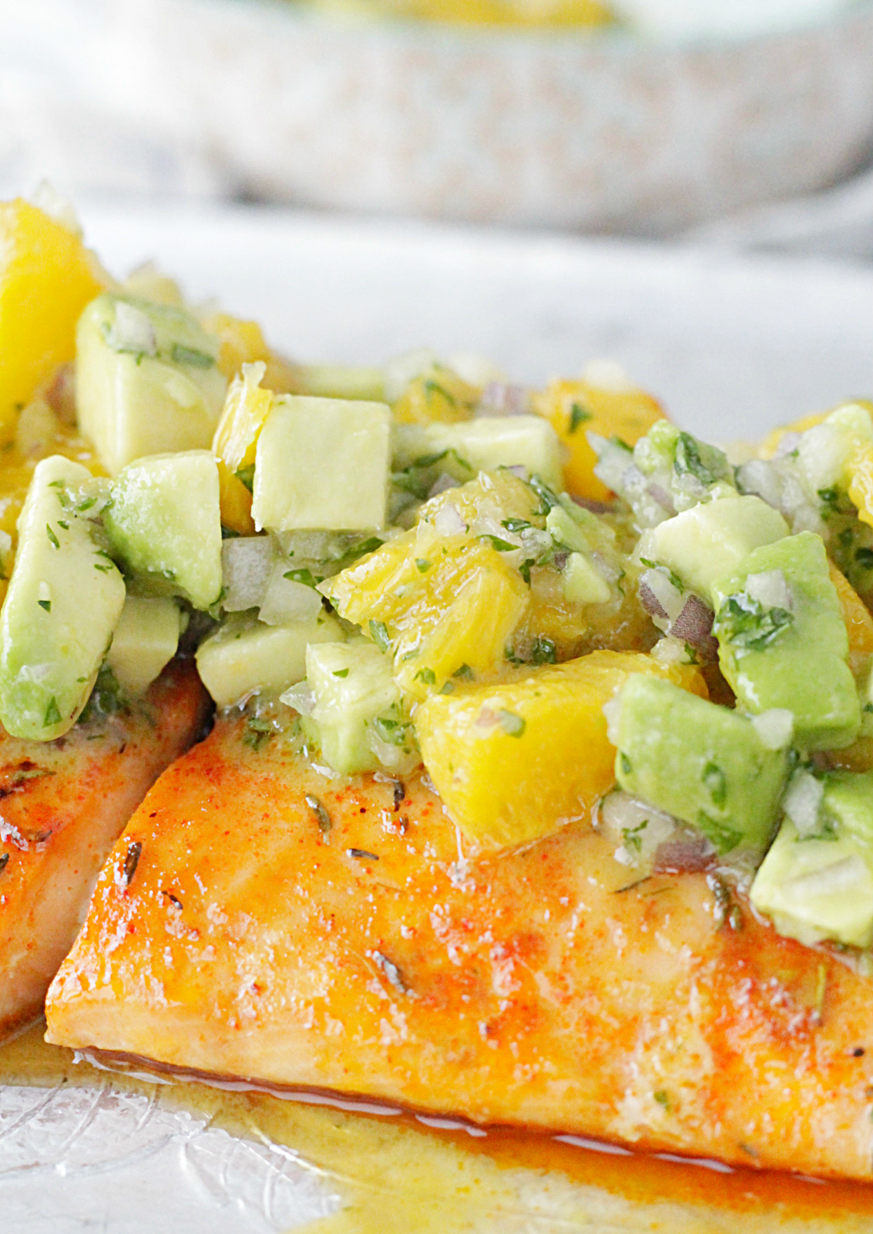 close up view of citrus salmon with avocado and orange salsa on top
