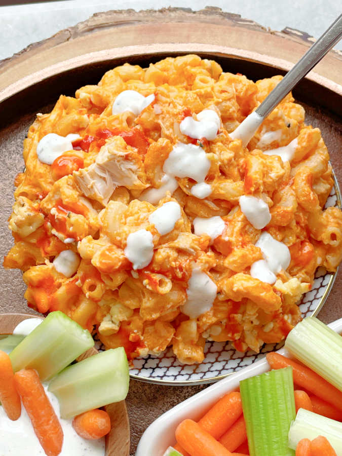 a plate of buffalo chicken mac and cheese drizzled with Ranch dressing