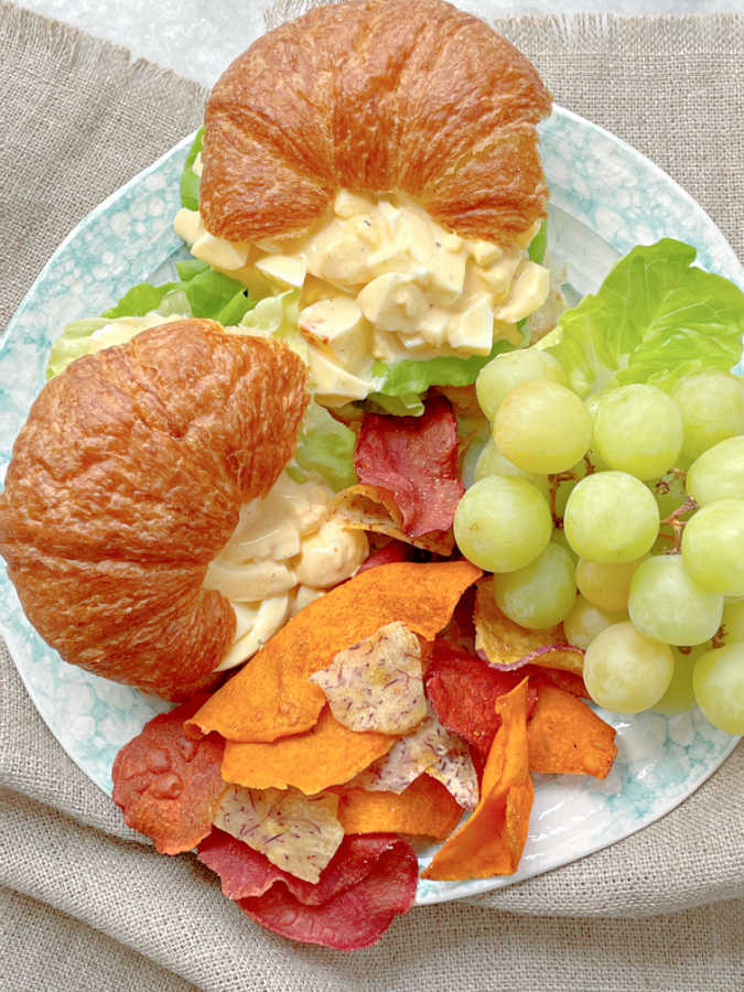 deviled egg salad sandwiches on a plate with chips and grapes