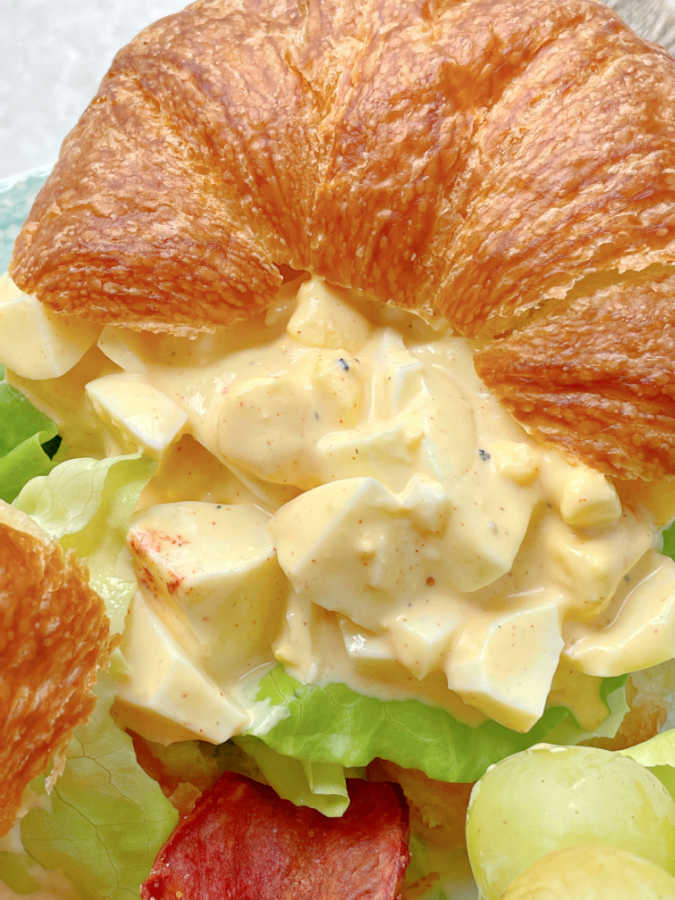 close up view of deviled egg salad on a croissant