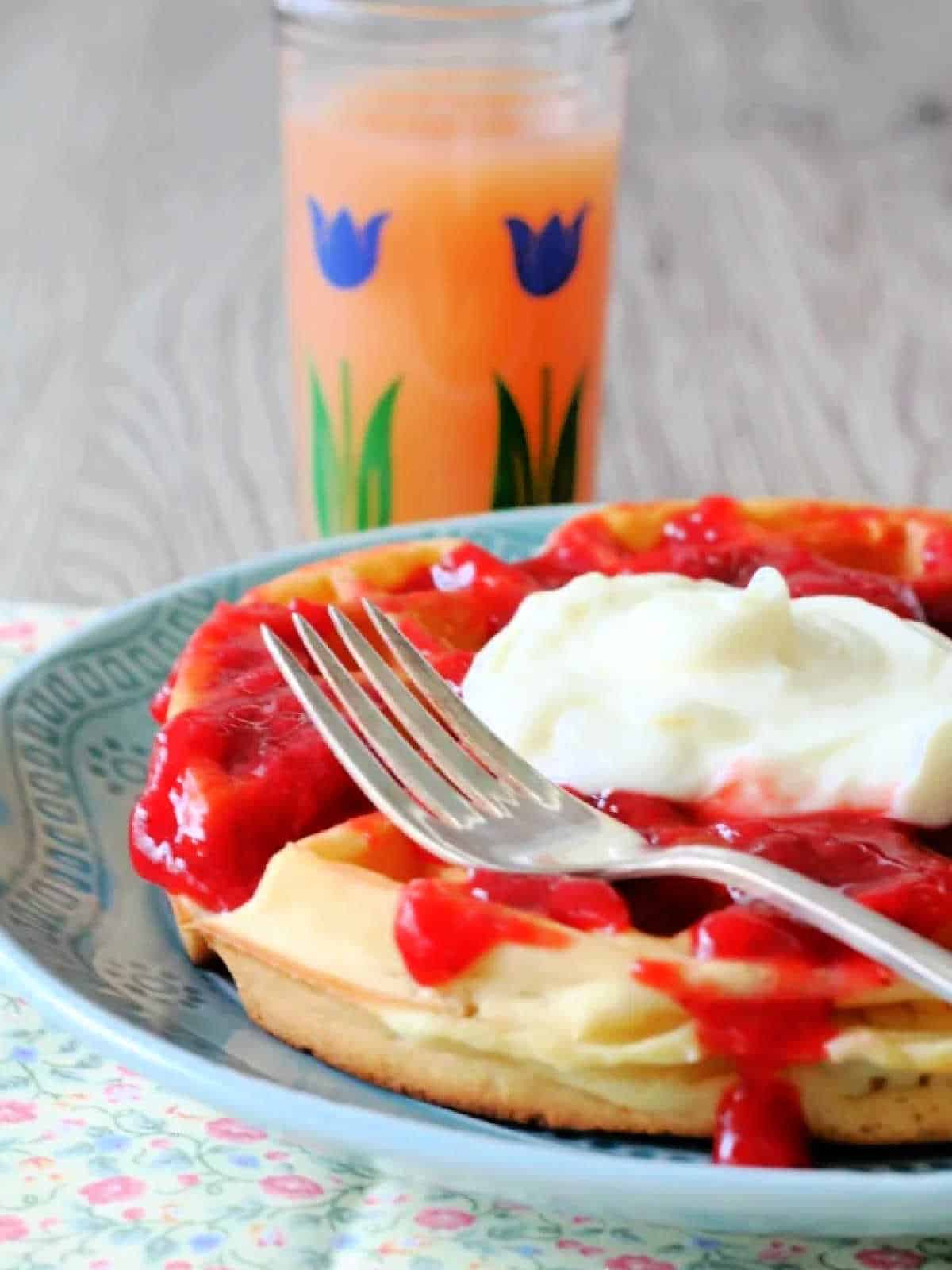 side view of homemade waffle topped with strawberry sauce and sweetened cream cheese
