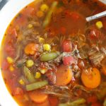 top view of beef vegetable soup in cream colored bowl