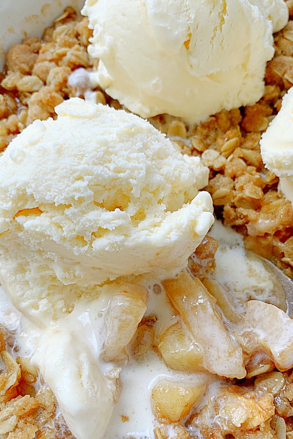 close up of a scoop of vanilla ice cream melting into apple crisp