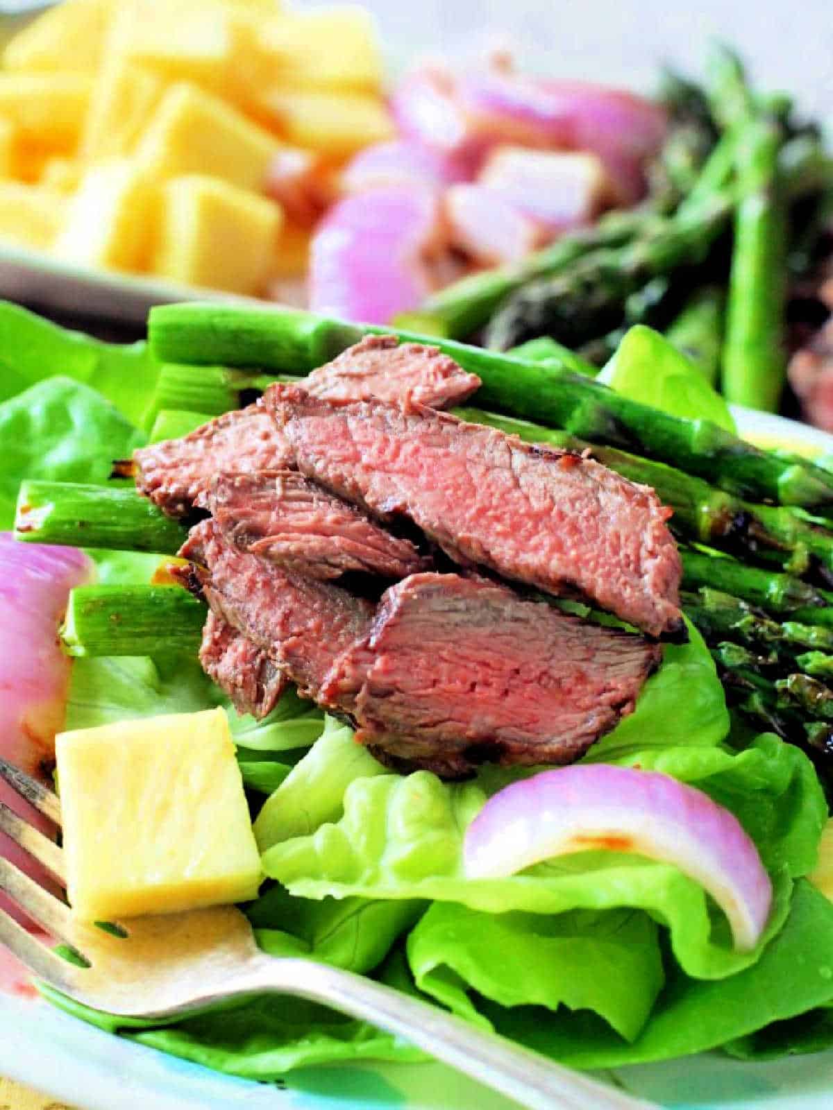 a close up picture of sliced steak atop the salad