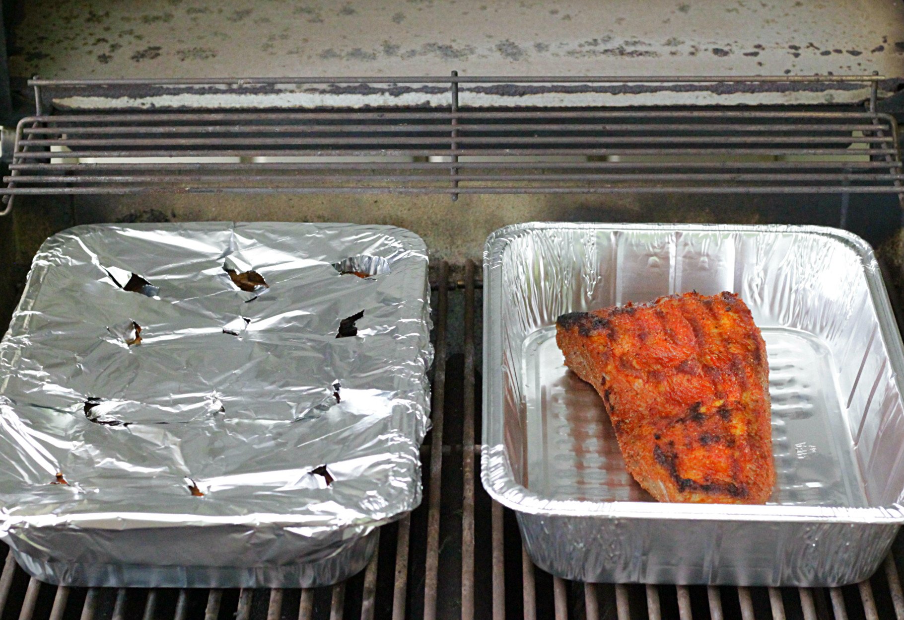 open grill with wood chips foil pan and brisket in process of grilling