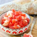 a decorative bowlful of canned tomato bruschetta on a board with baguette slices
