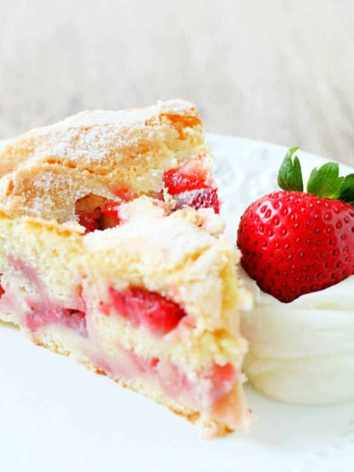 plated slice of french strawberry cake garnished with whipped cream and a fresh strawberry