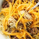 skyline chili over spaghetti and loaded with shredded cheddar cheese