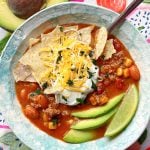 a bowl of slow cooker taco soup topped with tortilla chips, sour cream and shredded cheese