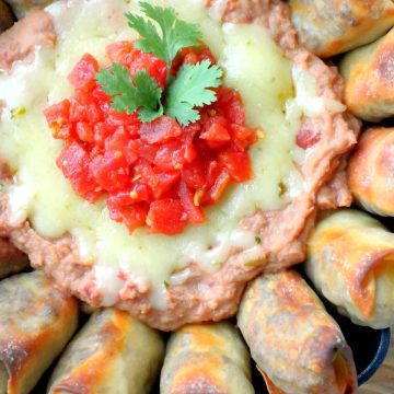 showing the bean dip topped with melted cheese and tomatoes in the skillet