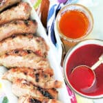 overhead view of a grilled pork tenderloin with a bowl of cherry bourbon glaze on the side