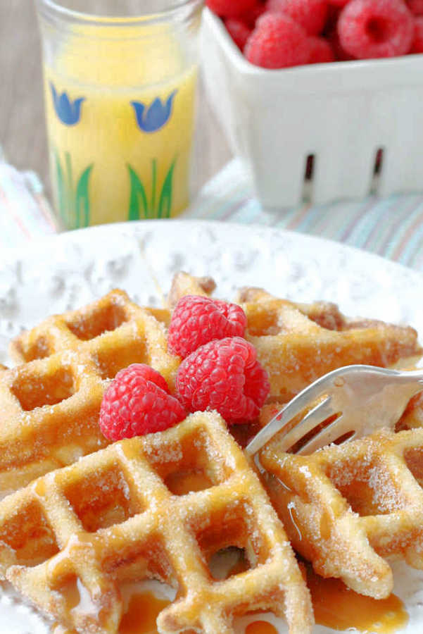 churro waffles topped with caramel sauce and raspberries