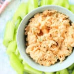 a bowl of buffalo chicken dip surrounded by fresh cut celery to dip