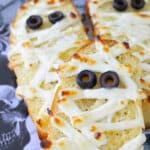 three mummified garlic breads on a skull plate