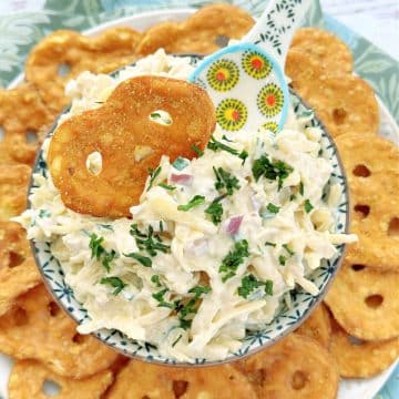jarlsberg cheese dip garnished with chop chives and surrounded by honey mustard pretzels