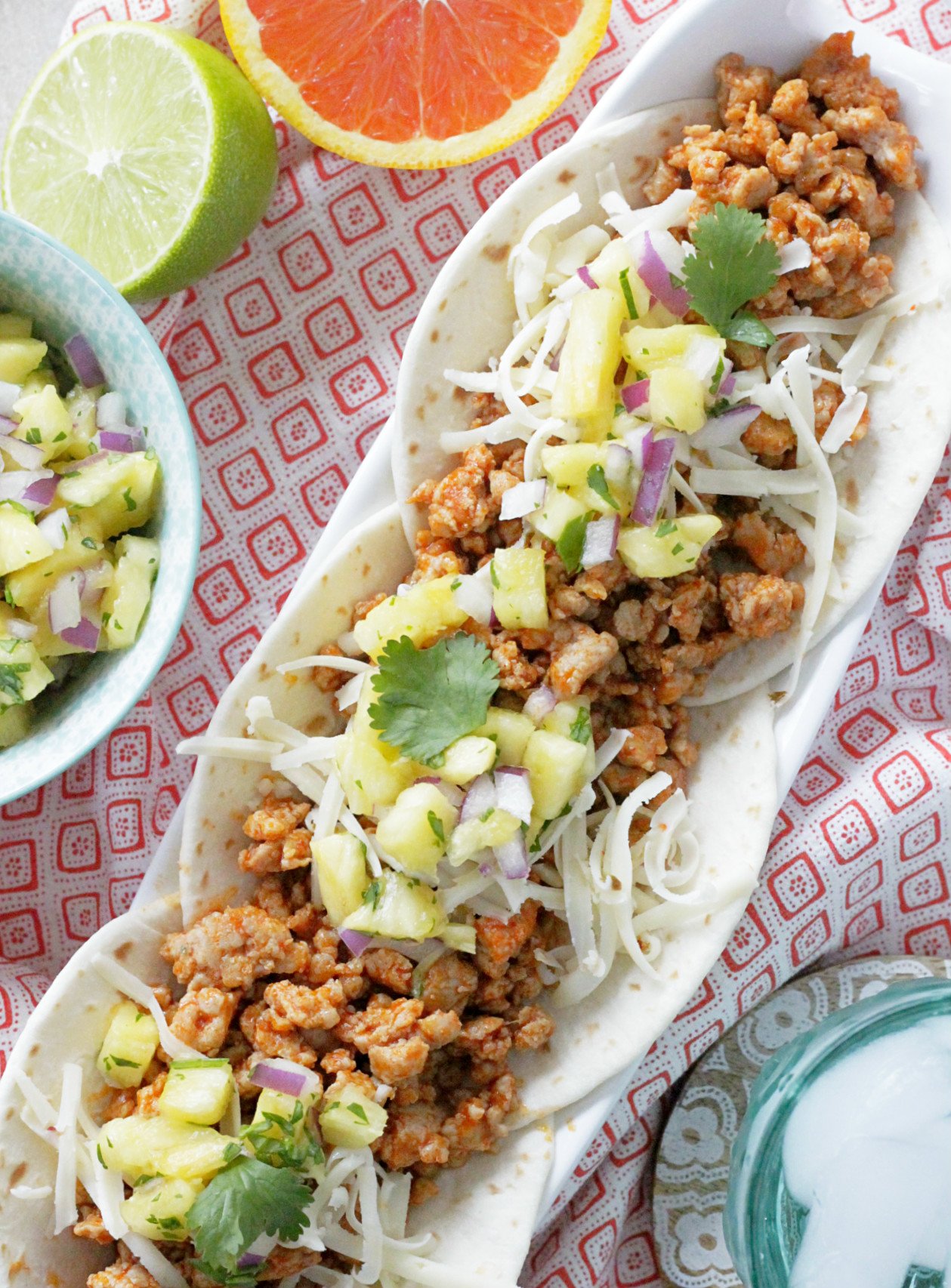 ground pork tacos with salsa, orange and lime halves