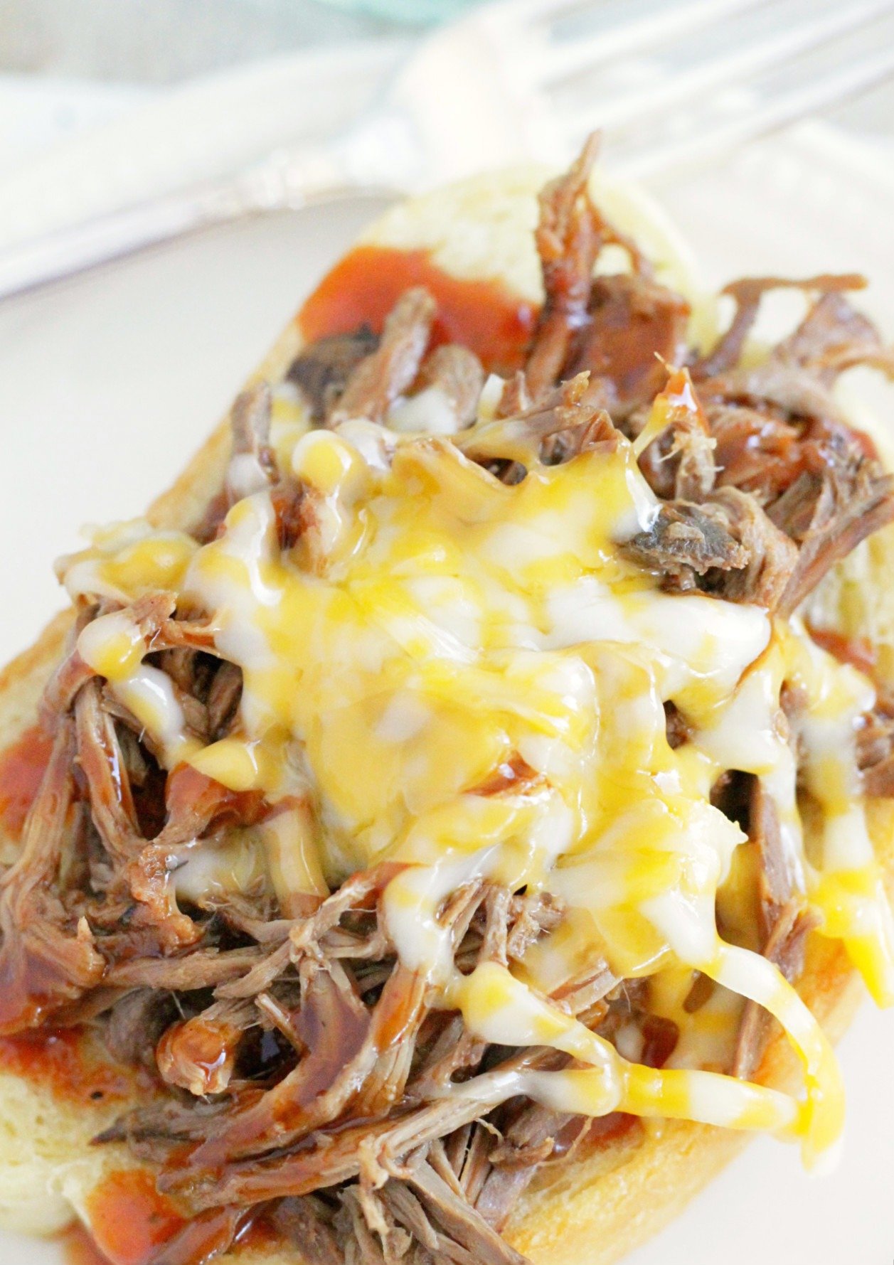 cook once eat all week with shredded beef top view of pile of bbq beef topped with melted colby jack cheese