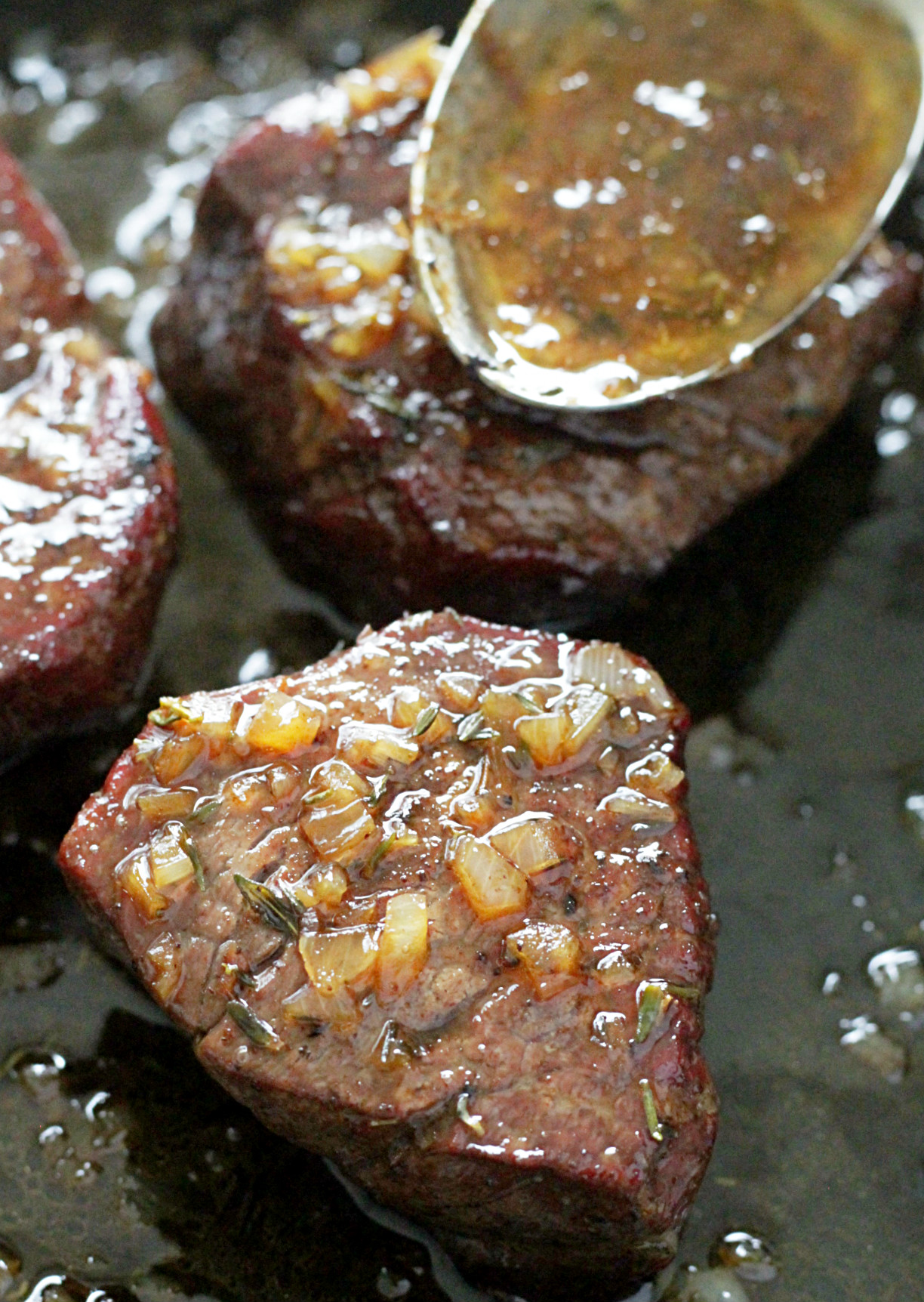 reverse sear filet mignon in skillet with sauce in spoon