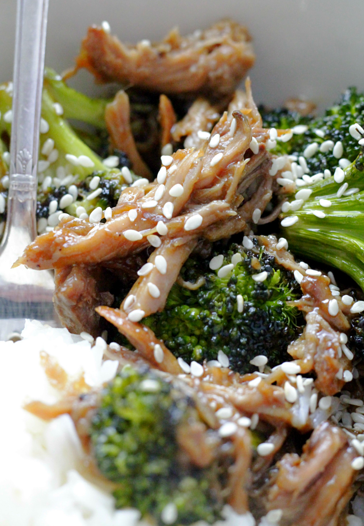 close up of pork teriyaki bowl in off-white bowl with fork