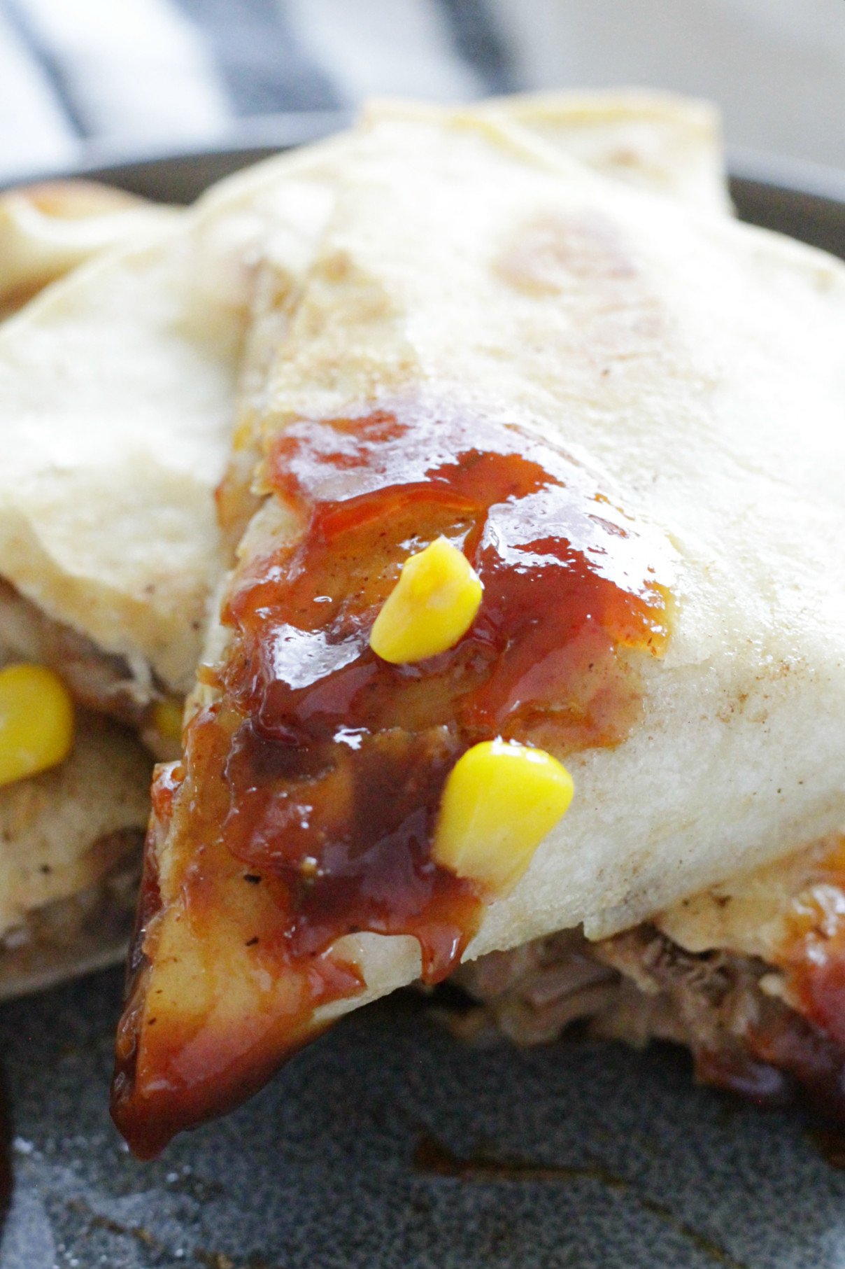 close up of bbq pork quesadilla on gray plate with smear of bbq sauce