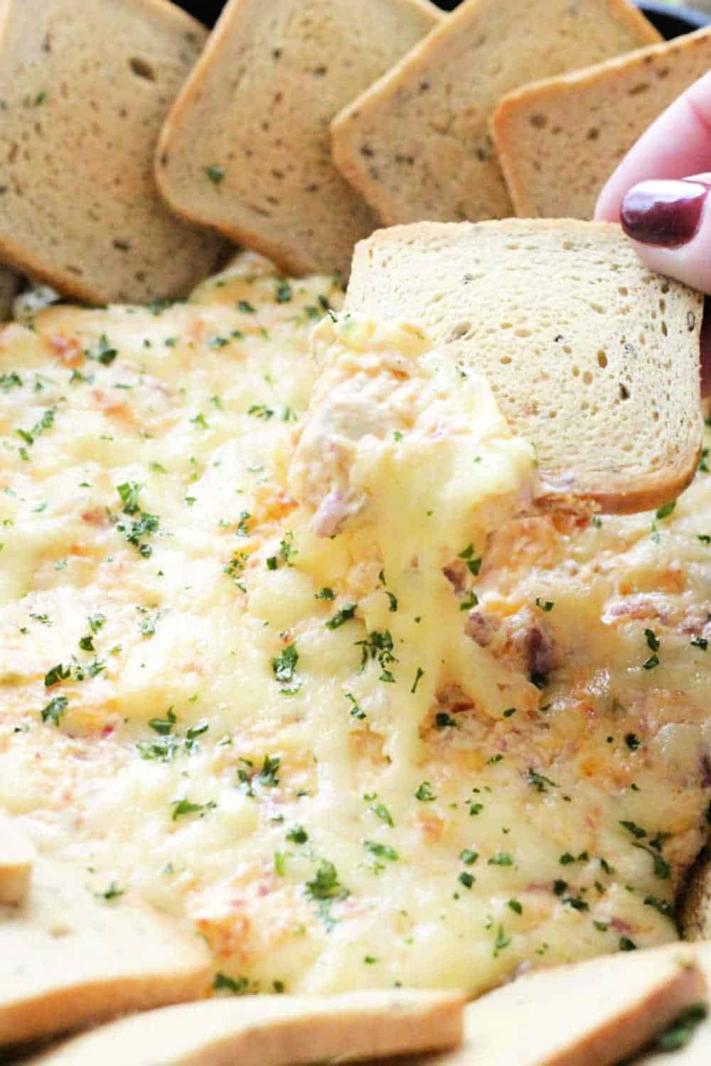 The ultimate reuben dip is baked in a skillet with toasty rye bread squares for dipping. Browning some deli corned beef and finely chopping the sauerkraut plus a couple of unusual mix ins combine for a crowd-pleasing dip based on the classic reuben sandwich. via @foodtasticmom