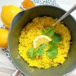 cooked turmeric rice in a pot garnished with lemon and cilantro