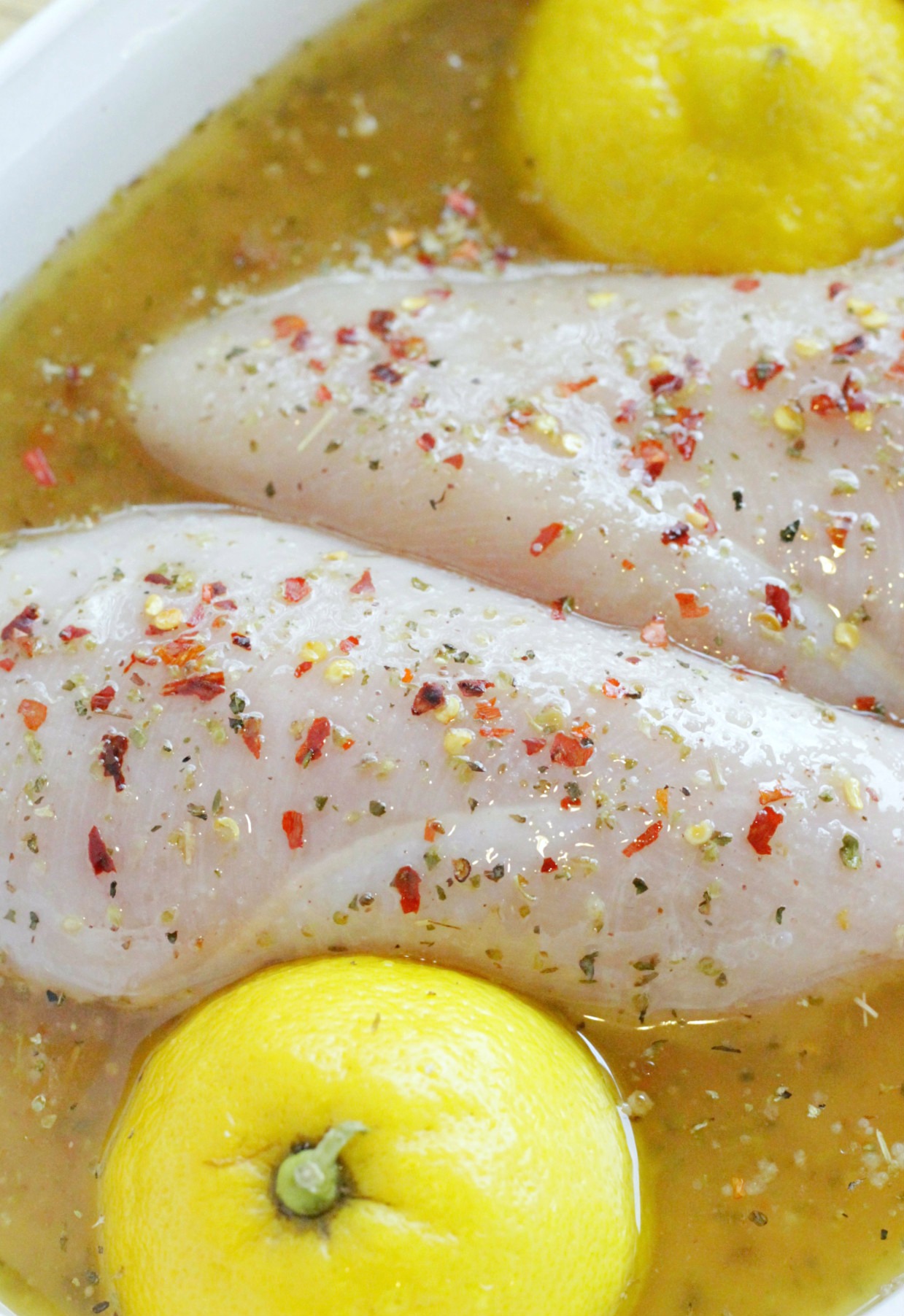 chicken and lemon halves in marinade for grilled lemon chicken Alfredo