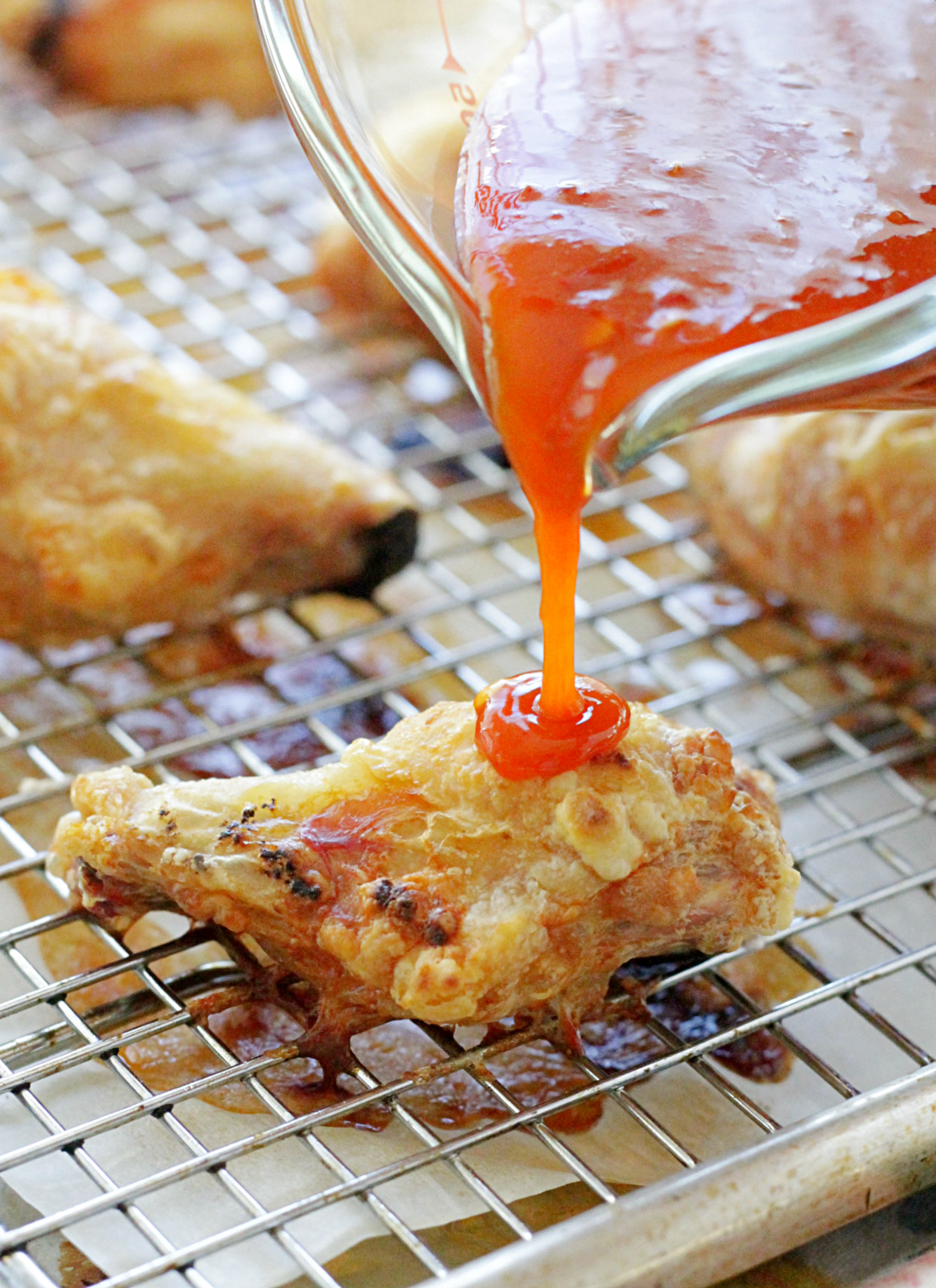 sauce being poured over the crispy baked chicken wings