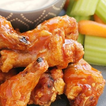 crispy baked chicken wings on a grey plate with celery carrots and blue cheese dressing