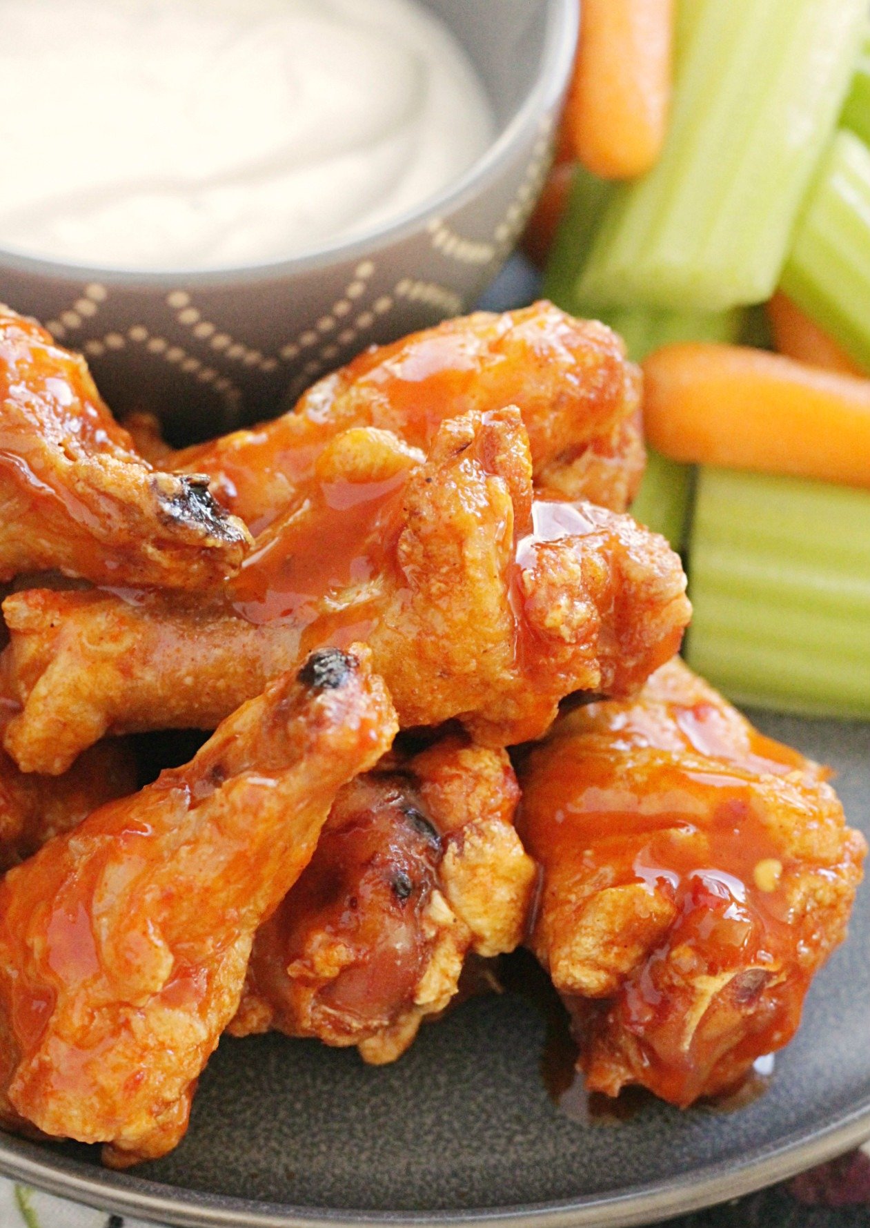 crispy baked chicken wings on a grey plate with celery carrots and blue cheese dressing