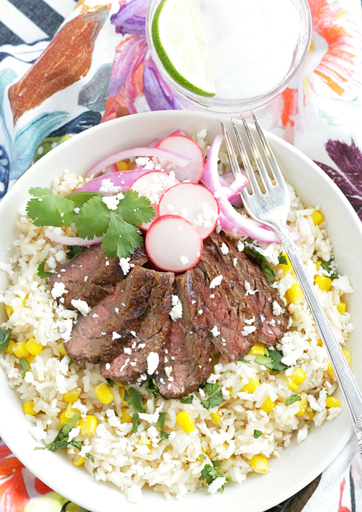 grilled carne asada burito bowls - overhead view of burrito bowl with glass of water with lime slice