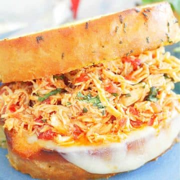 These Slow Cooker Italian Chicken Sandwiches have a fresh tomato flavor even when tomatoes aren't in season. Slow cooked Italian-flavored chicken is piled high on toasty garlic bread with melted Provolone cheese and fresh chopped basil.