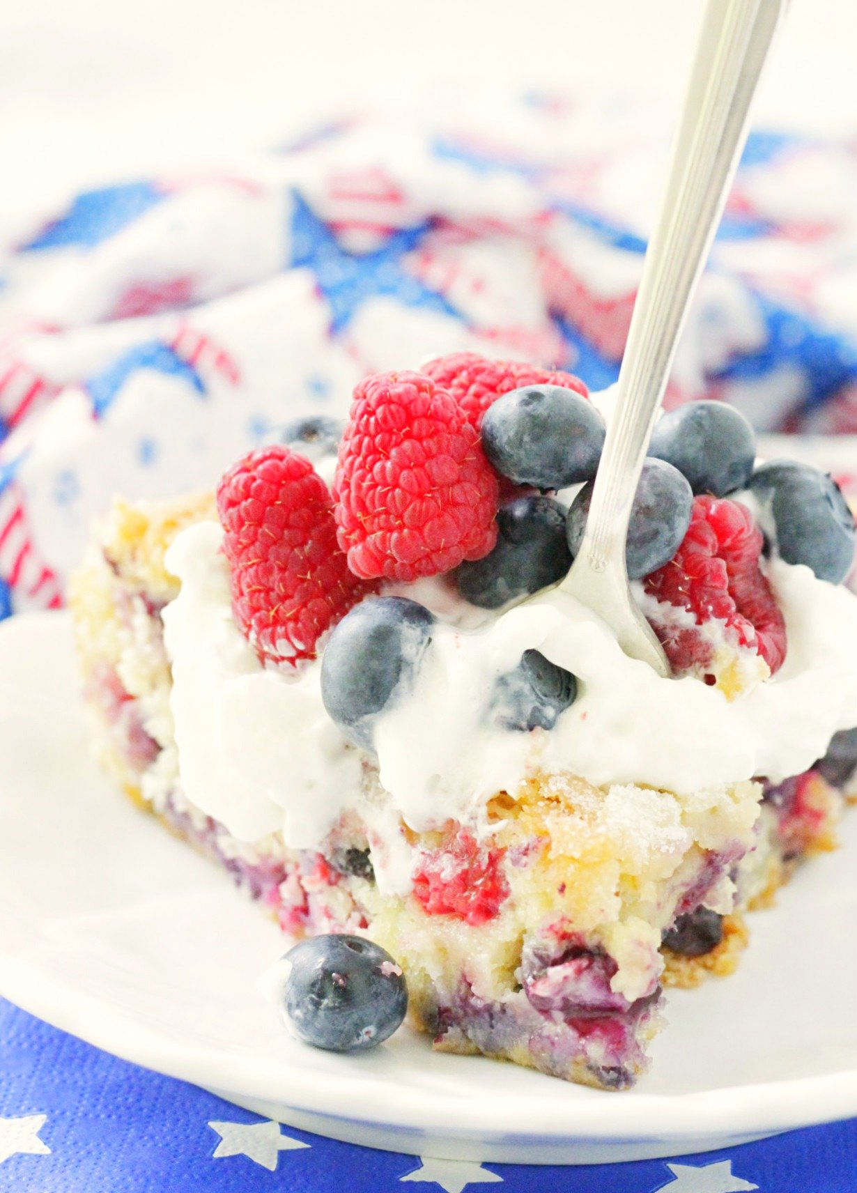 front view of slice of red white and blue berry cake on plate