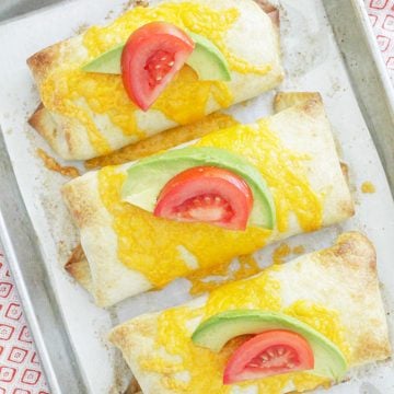 oven fried chimichangas overhead baked on sheet pan and topped with fresh tomato and avocado