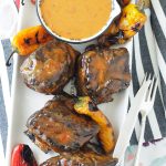 grilled short ribs with asian peanut sauce overhead view of platter with bowl of sauce and grilled short ribs and peppers