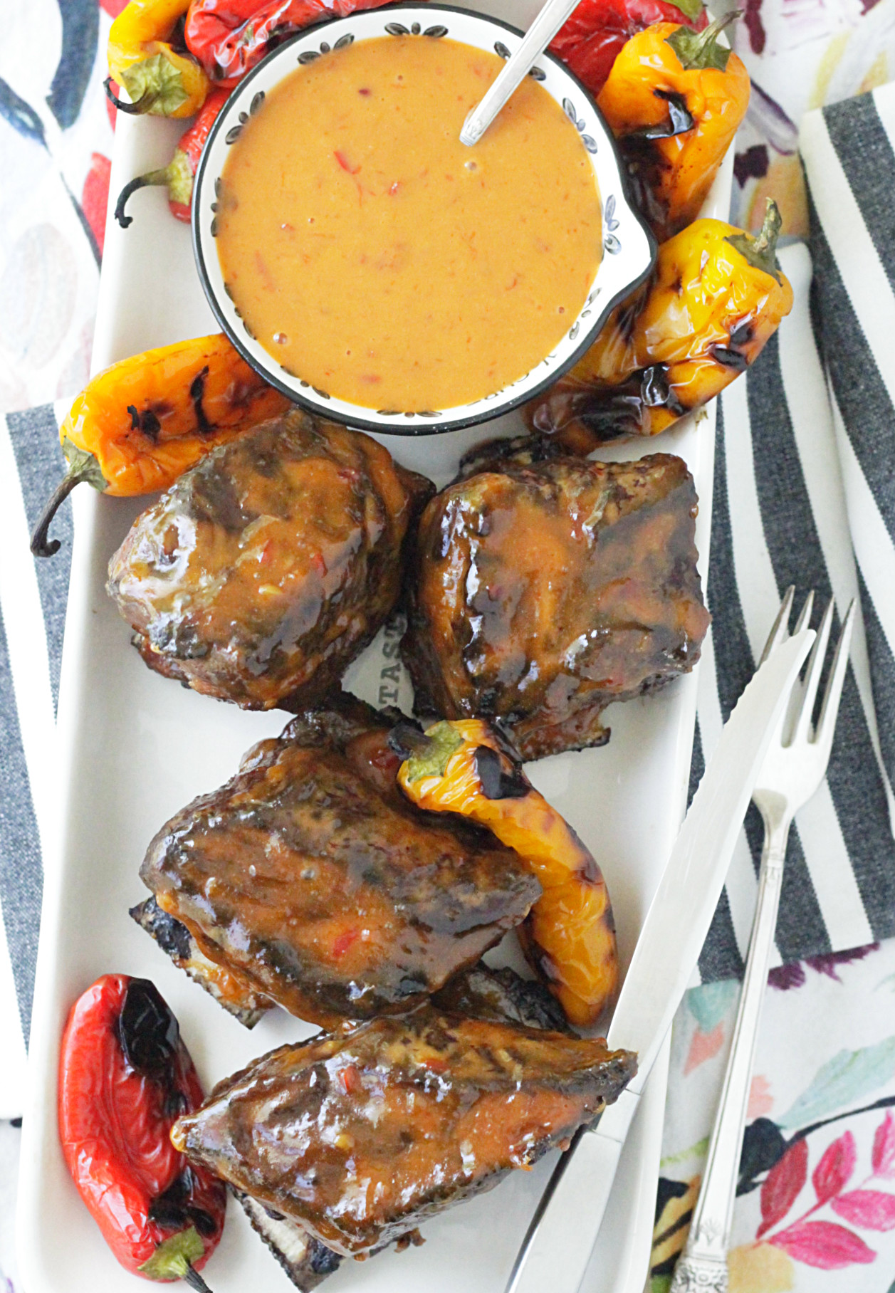 grilled short ribs with asian peanut sauce overhead view of platter with bowl of sauce and grilled short ribs and peppers