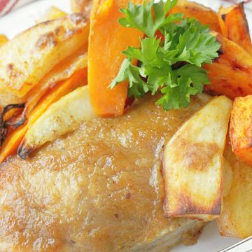 close up of applesauce baked pork chop on a plate with roasted potatoes