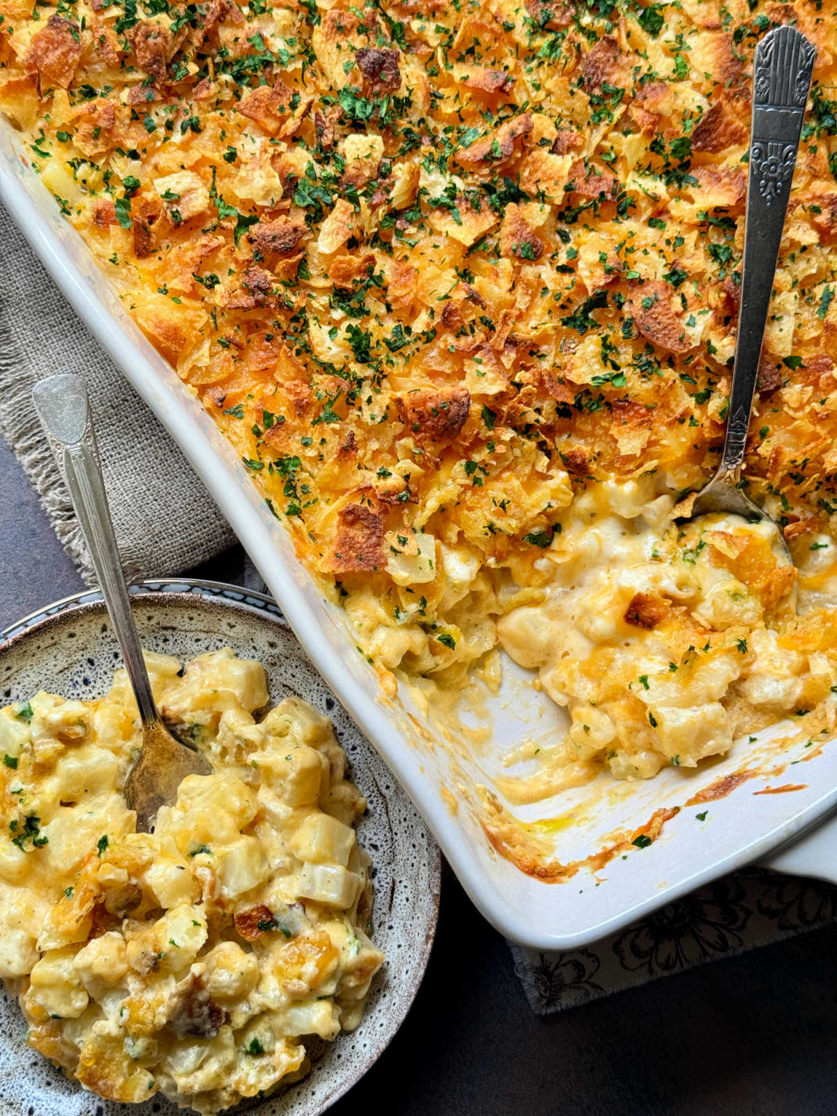 a dish of cheesy potatoes side by side with the casserole dish it was served from